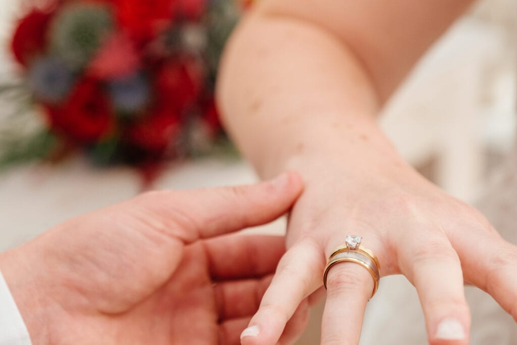 Detail foto van ring die aan de vinger wordt aangedaan tijdens huwelijksplechtigheid
