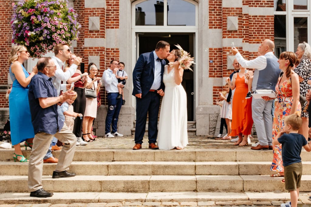 Bruid en bruidegom kussen elkaar voor stadhuis van Landen