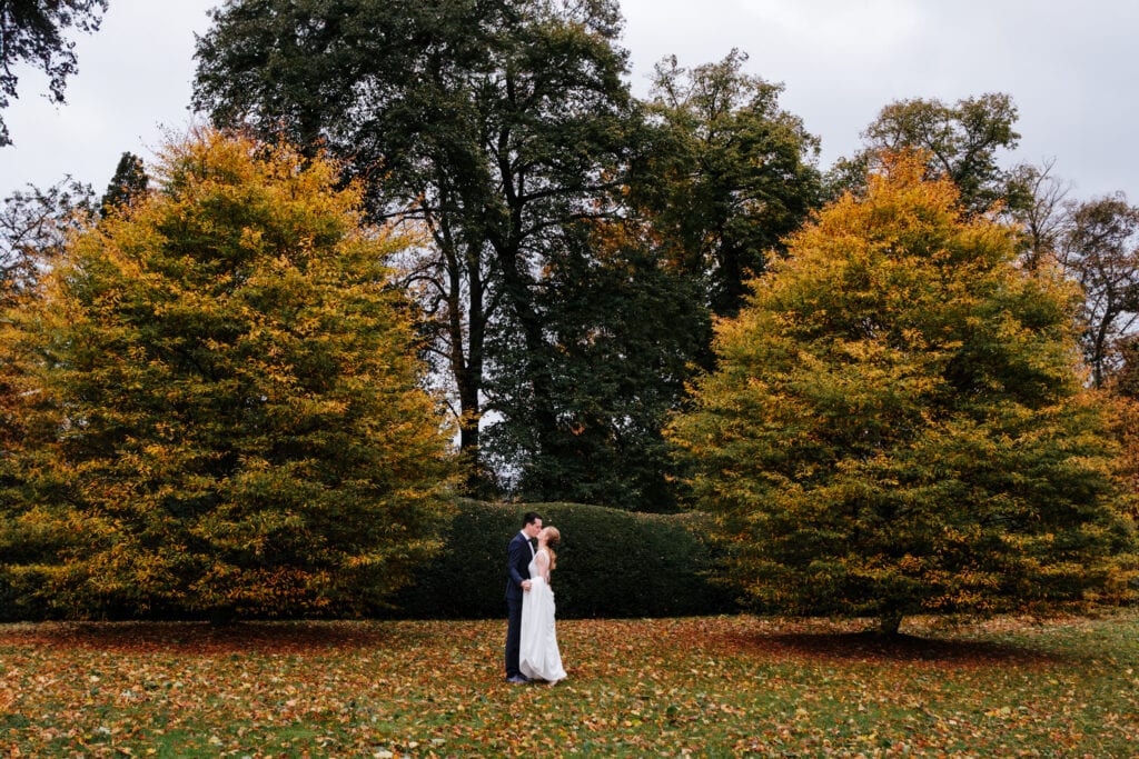Wide bruidspaar tussen de oranje gekleurde bomen in de herfst